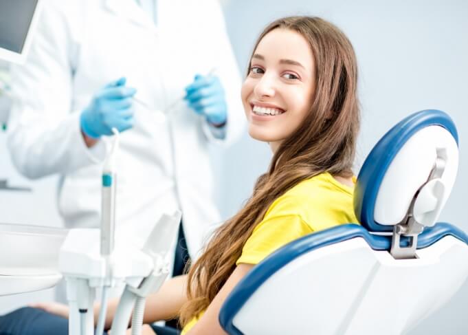 Woman in yellow blouse smiling in dental chair