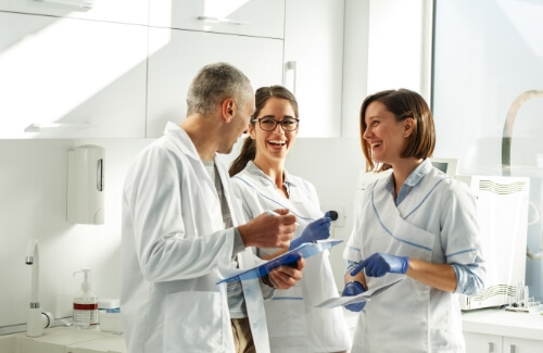 Three dentists in white lab coats having discussion