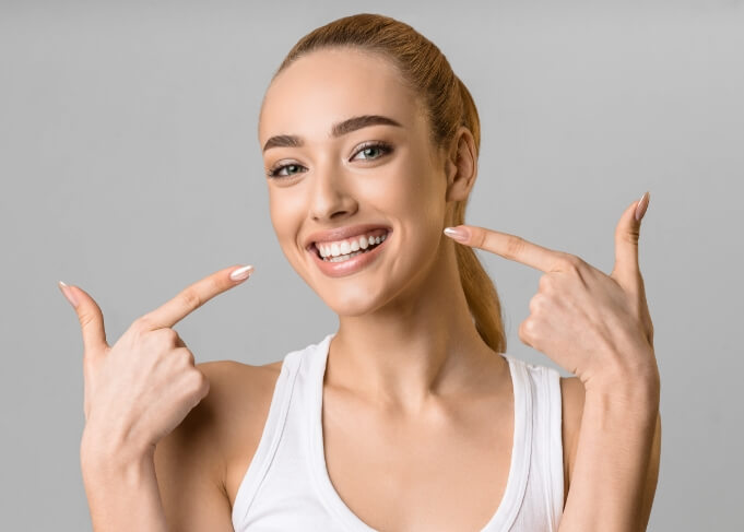 Woman with ponytail pointing to her smile after cosmetic dentistry in Grantsville