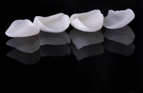 Four white dental crowns against black background