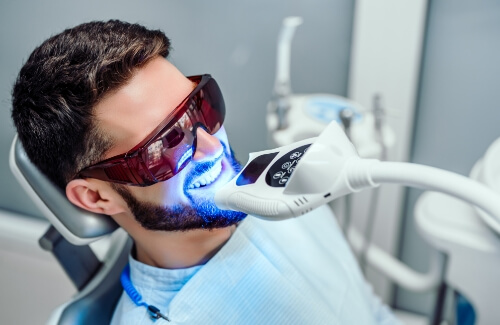 Man in dental chair receiving professional teeth whitening