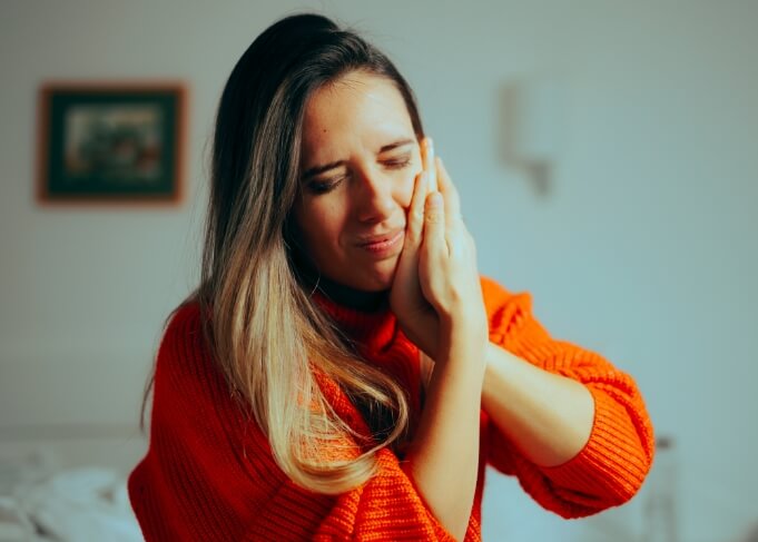 Woman wincing and holding her cheek in pain needing emergency dentist in Grantsville