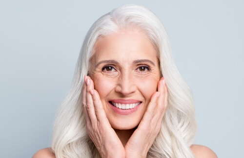 Smiling senior woman touching her face