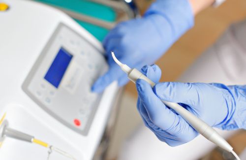 Gloved hands holding a dental laser device