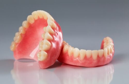 Two full dentures resting on gray surface
