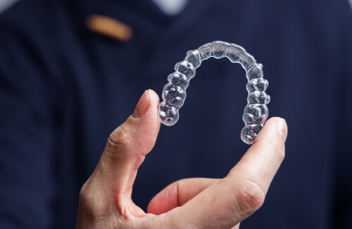 Hand holding an Invisalign clear aligner