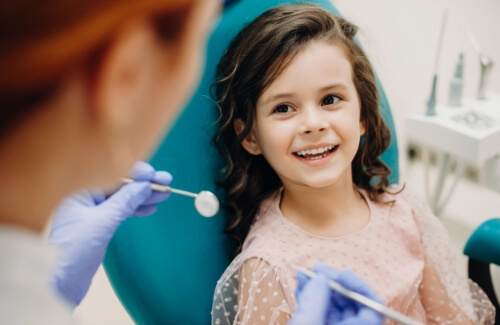 Young girl in dental chair smiling at her dentist