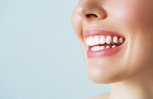 Nose-to-neck ¾ profile view of woman smiling with bright white teeth