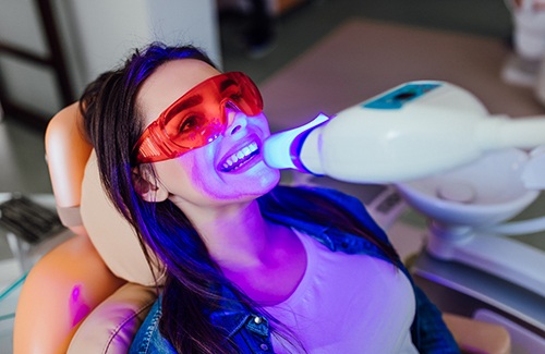 Woman in dental chair with UV light applied to teeth whitening