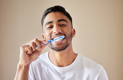 Man brushing teeth with beige background
